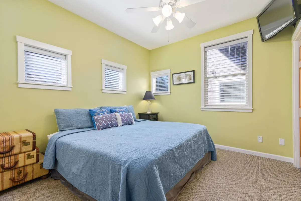 A calm and inviting bedroom featuring a plush bed with decorative pillows, warm natural light streaming through windows, and a bedside lamp, creating an intimate space ideal for relaxation and restful sleep.