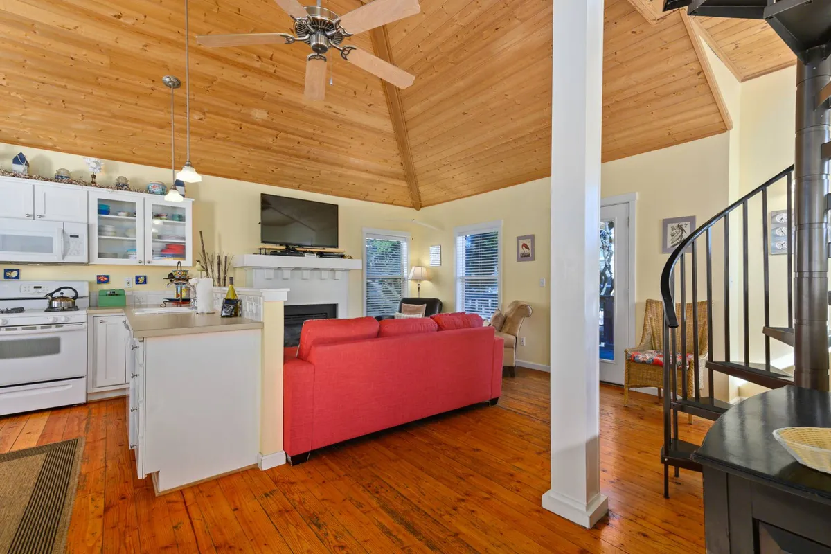 This interior scene features a striking spiral staircase next to a red sofa and cozy kitchen area. The wooden ceiling and open layout create a playful and inviting atmosphere, while the spiral staircase hints at secret spaces above—perfect for the crow's nest and Eyeful Tower.